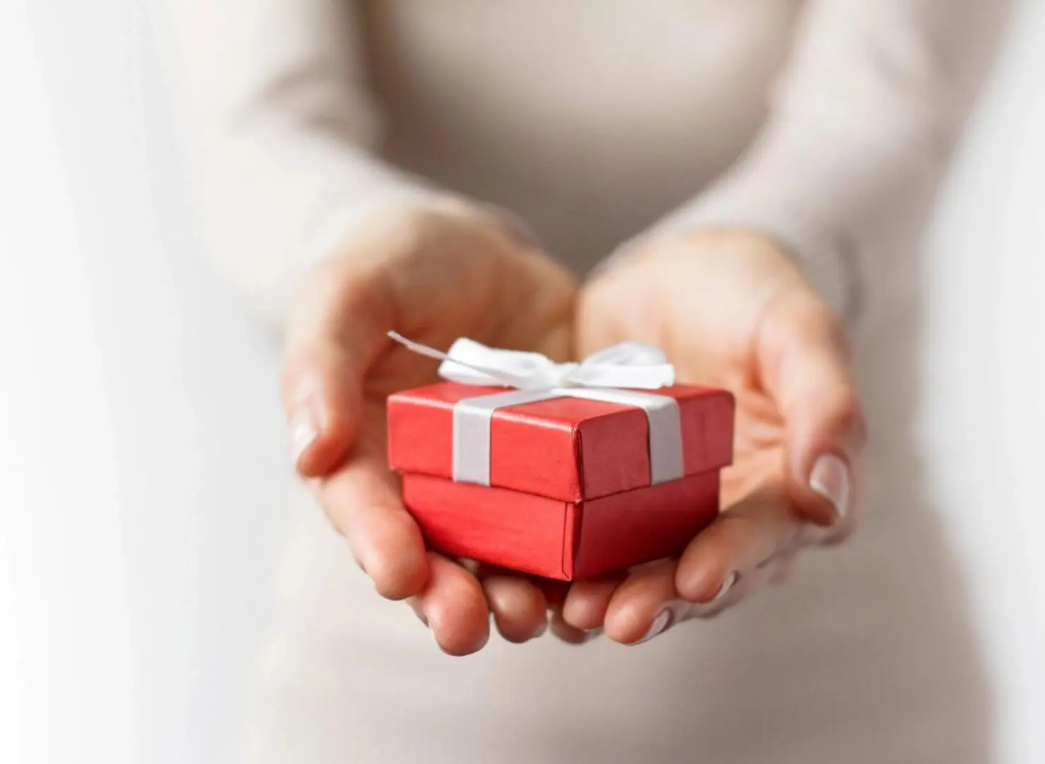 A person holding a small red gift box.